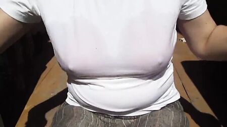 A rapariga tira o sutiã de banho molhado por baixo da t-shirt molhada