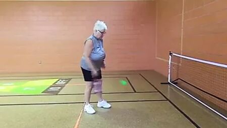 Mulher madura sem sutiã, com seios enormes e caídos, a jogar pickleball
