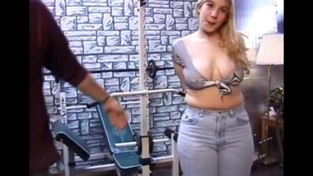 Uma mulher de cabelos longos com peitos naturais examina o pênis de um homem